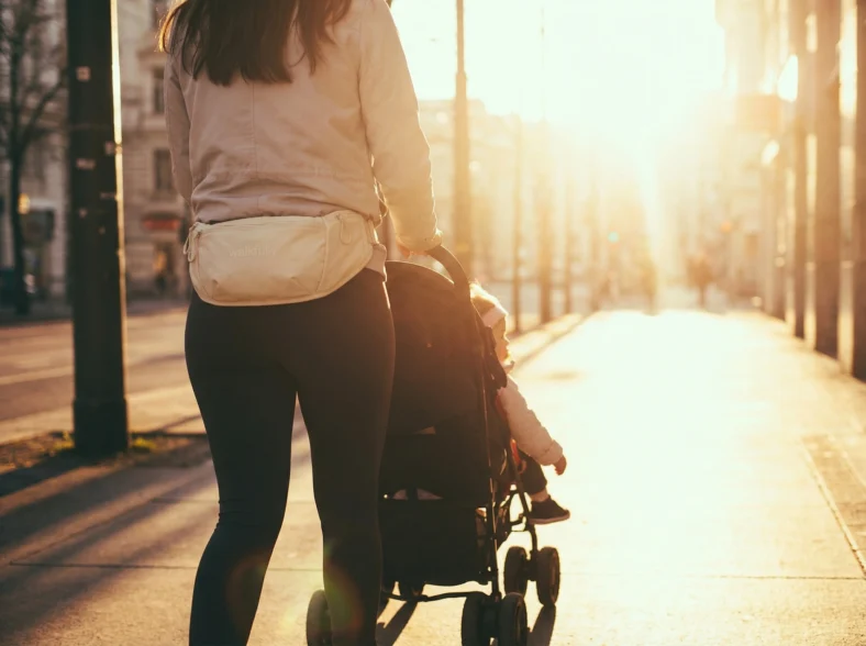woman pushing a baby stroller wears a WalkFully vest