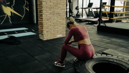 woman sits on a tire in the gym