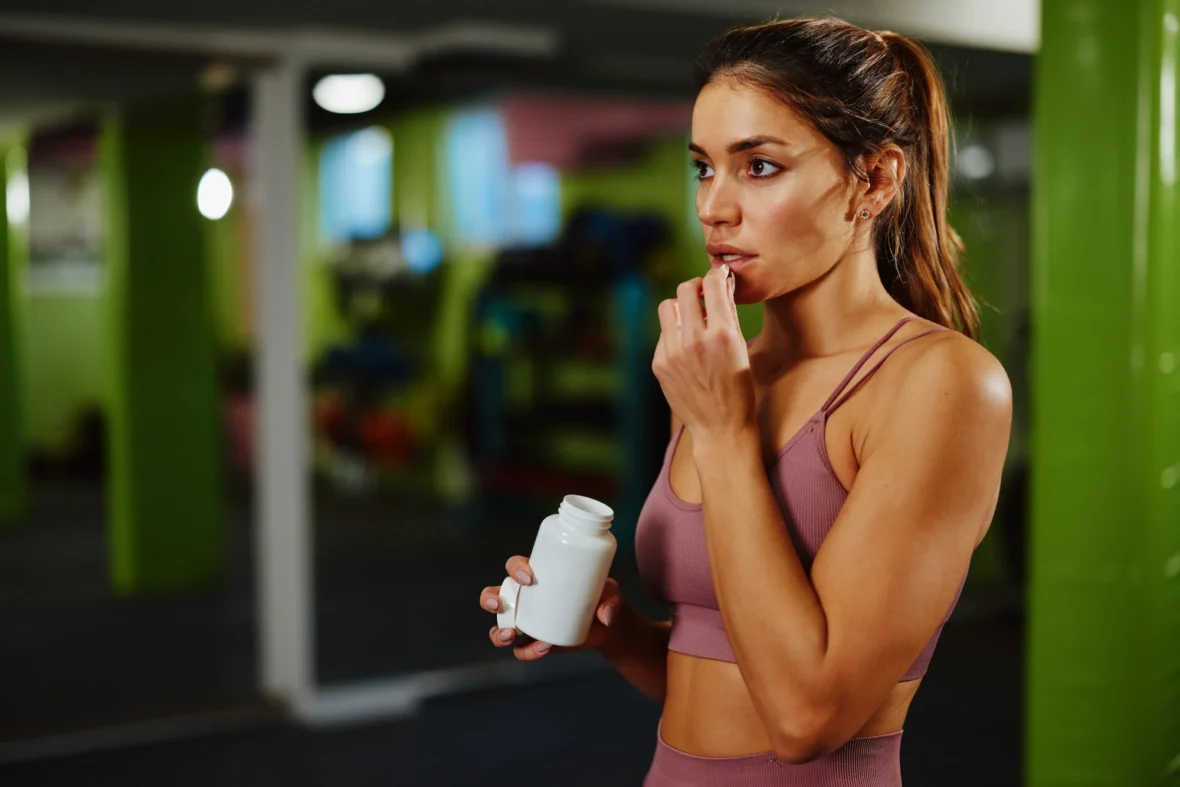 woman takes a supplement at the gym