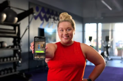 woman holds an iPhone showing Apple Fitness+