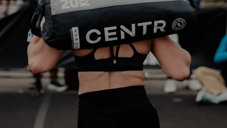 woman carries a sand bag at a Hyrox event
