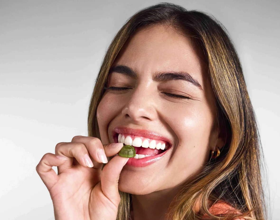 woman eats an AG1 gummy