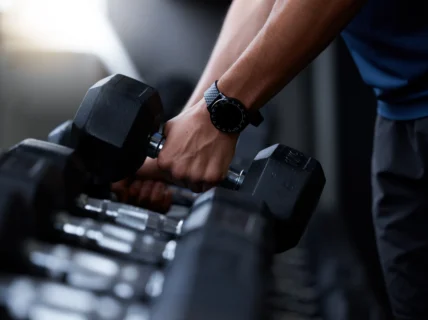 man wears a wearable while picking up a dumbbell