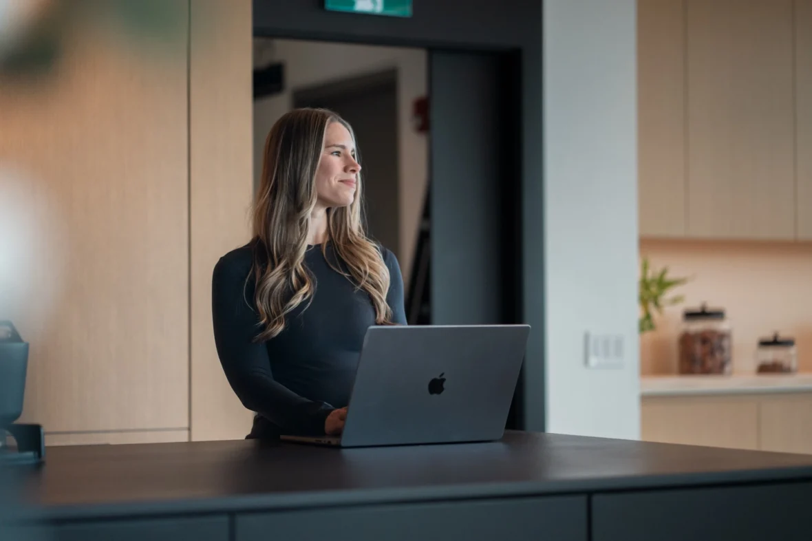 woman stands at a desk with a laptop